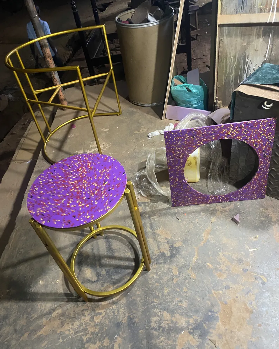 Purple recycled plastic stool beside a gold chair frame